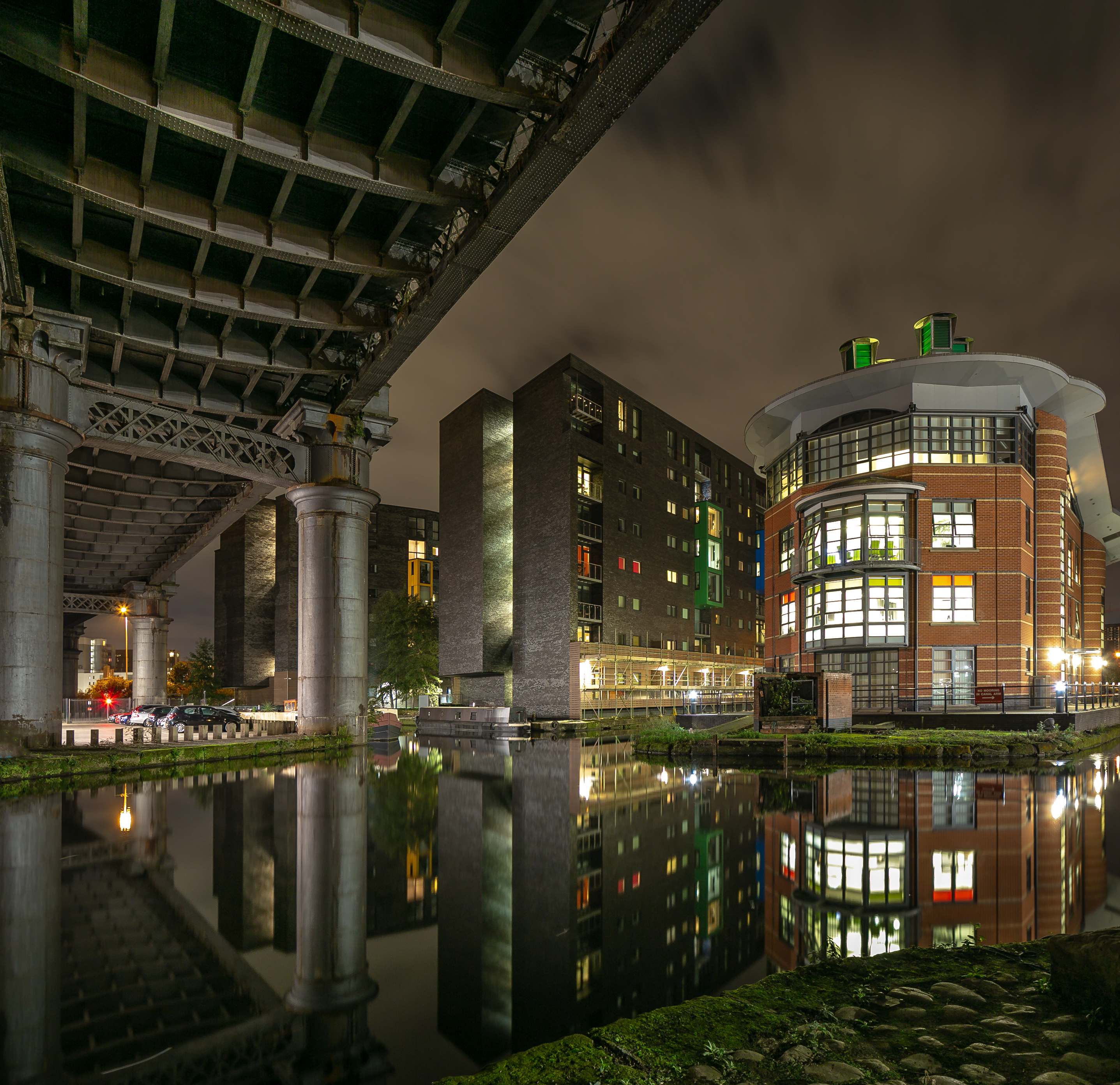 Canal Side building lit up in the dark night sky, that are reflected in the canal side setting in Manchester City Center, UK.  Architectural Photography taken by Di Jones Photography.